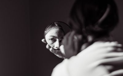 Dark photo of a girl's face reflected in a small round mirror to illustrate the article 